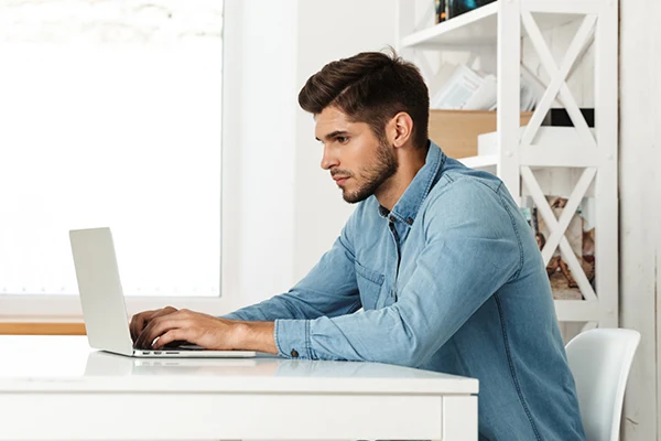 man in blue collared shirt working at laptop on EarthLink business internet